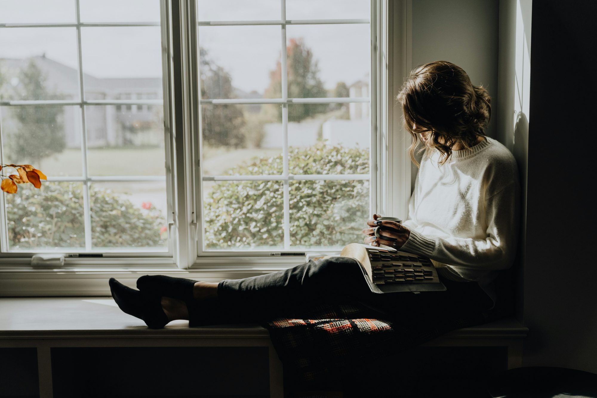 Mujer leyendo sentada en el alféizar de una ventana