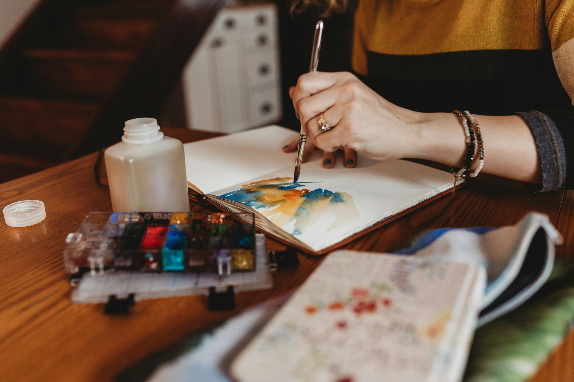 Manos pintando con acuarelas en un cuaderno