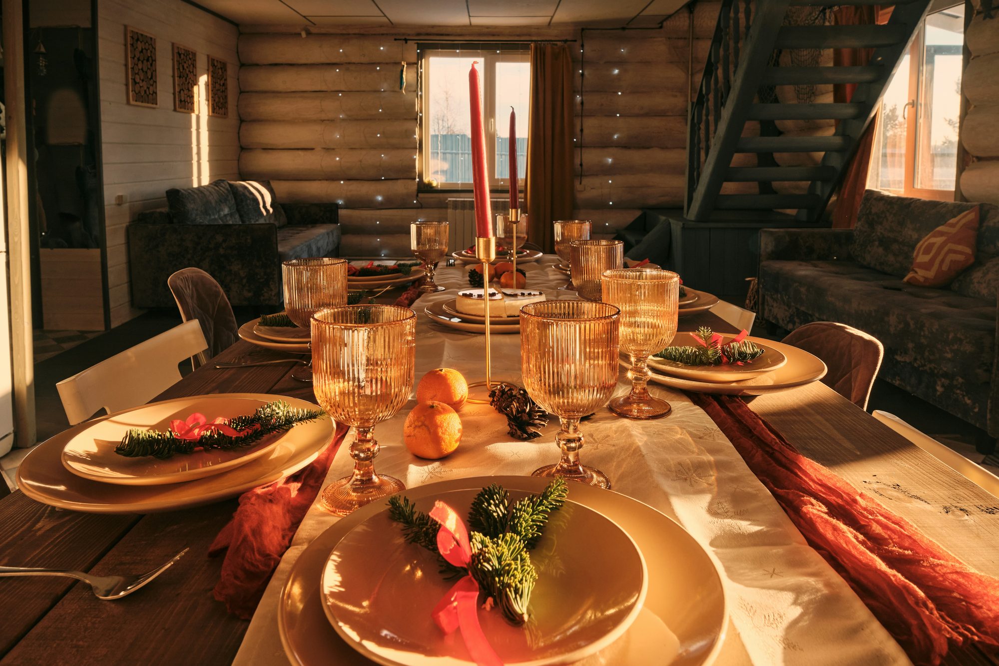 Mesa de comedor puesta con velas y copas en una cabaña de madera