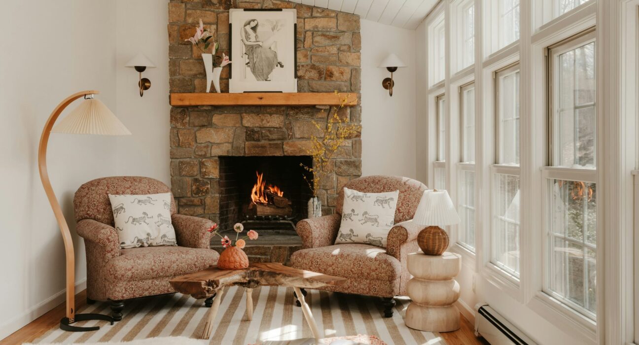Salón luminoso con chimenea de piedra encendida y dos butacas