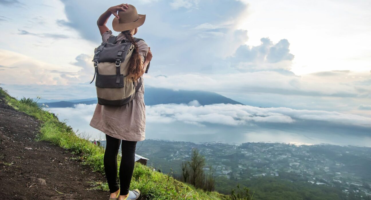 Viajera con mochila y sombrero mirando el valle desde un sendero