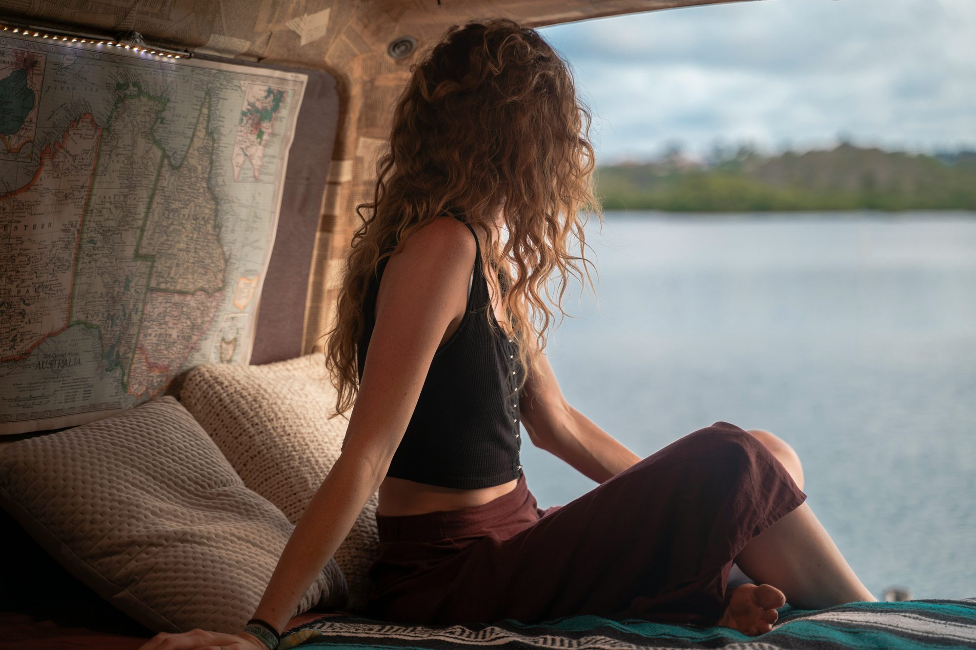 Mujer sentada en una camper mirando un lago