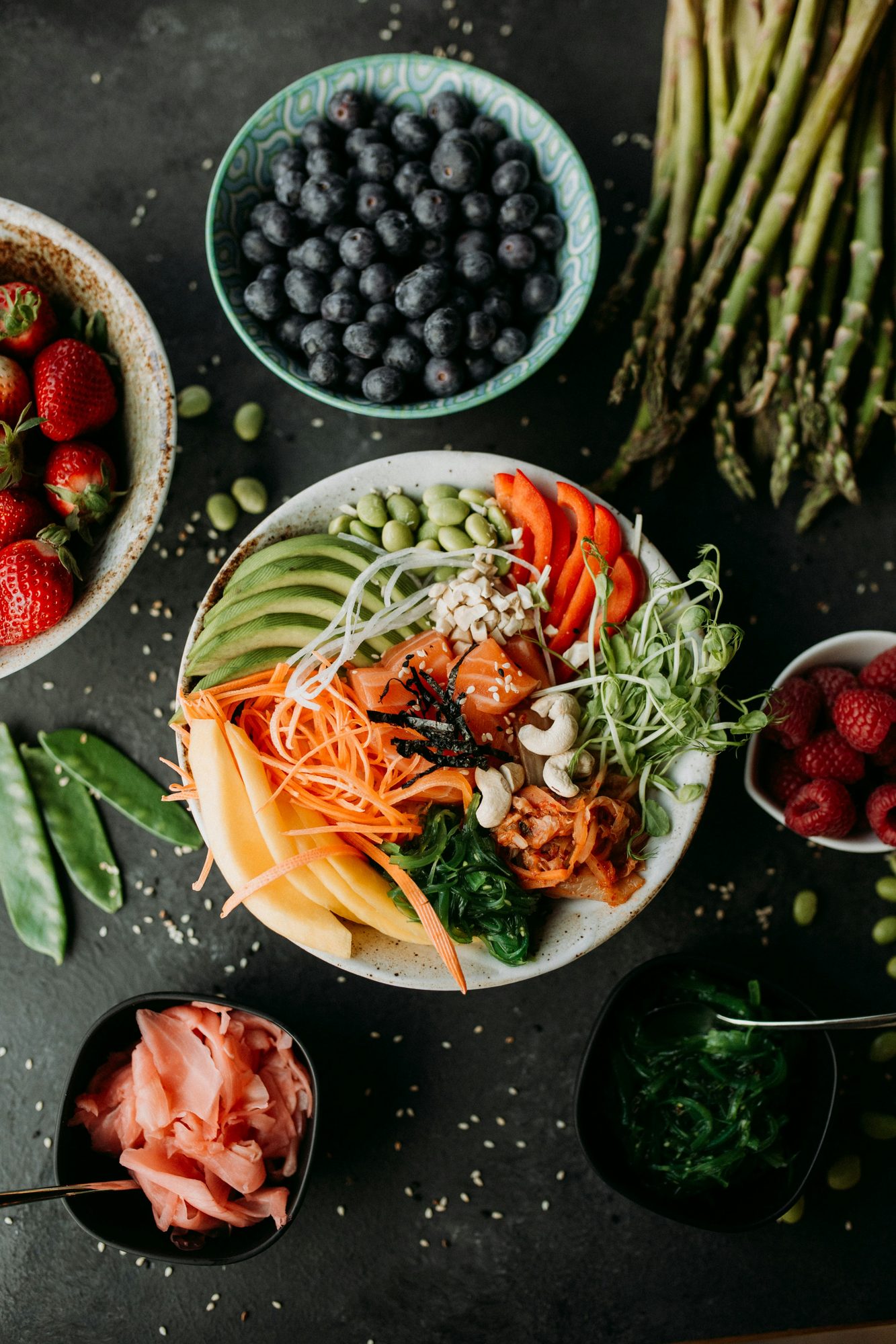 Bowl con salmón, aguacate, verduras y frutos rojos alrededor