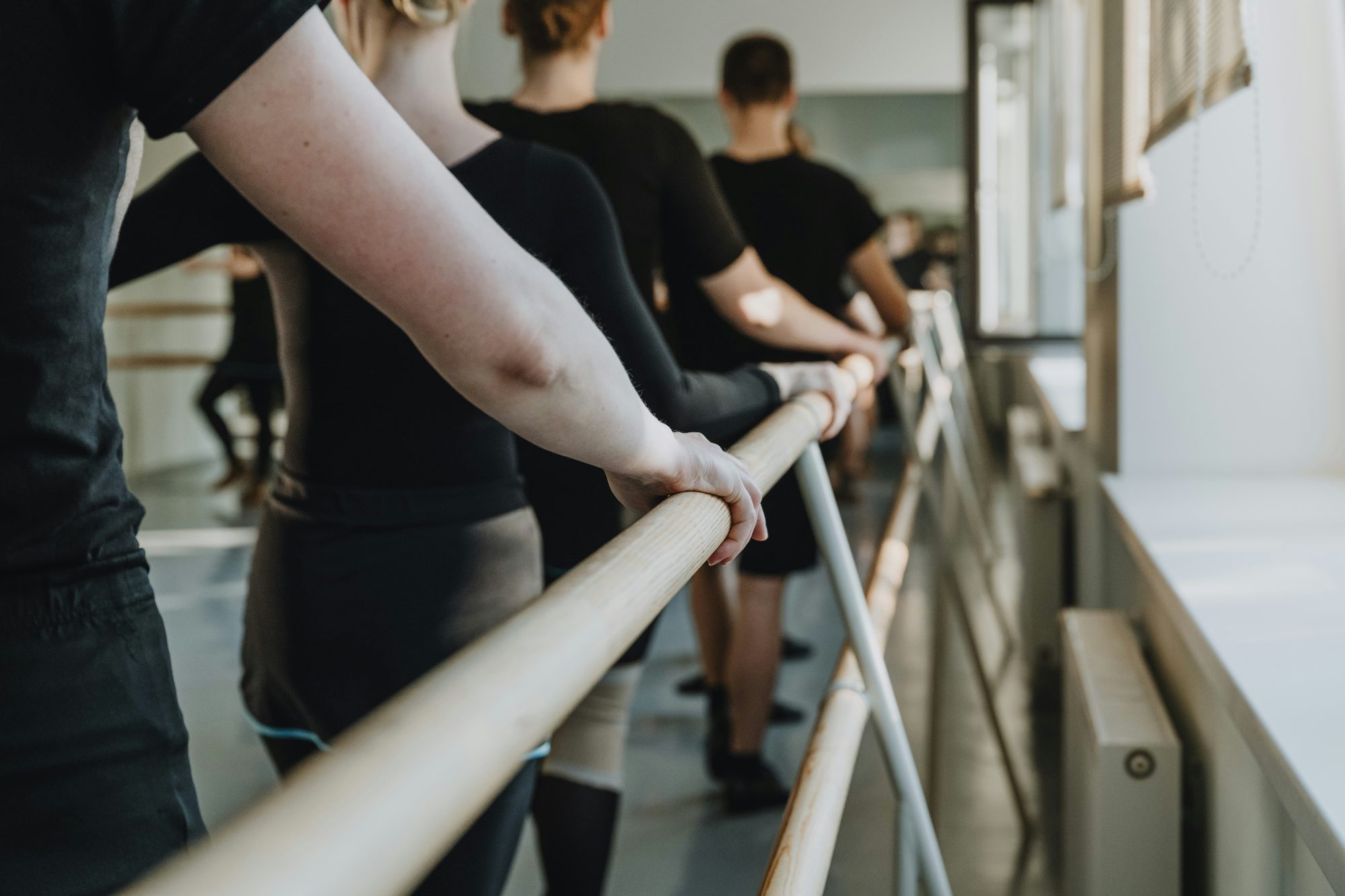 Alumnas apoyadas en la barra durante una clase de barre