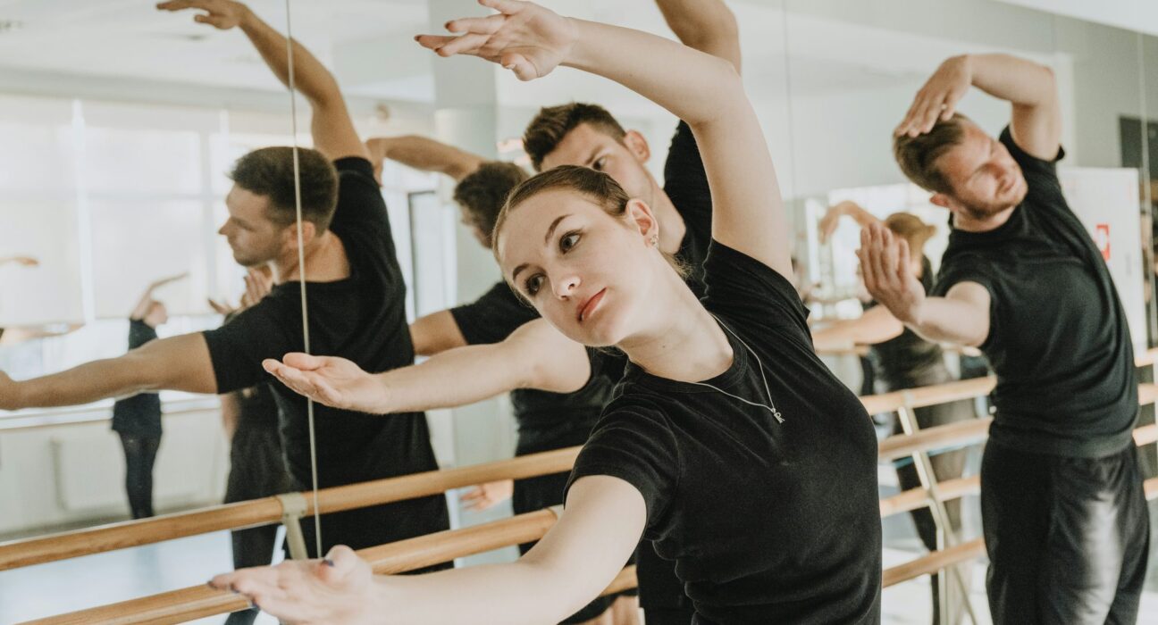 Clase de barre con alumnos estirando el brazo frente al espejo