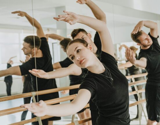Clase de barre con alumnos estirando el brazo frente al espejo