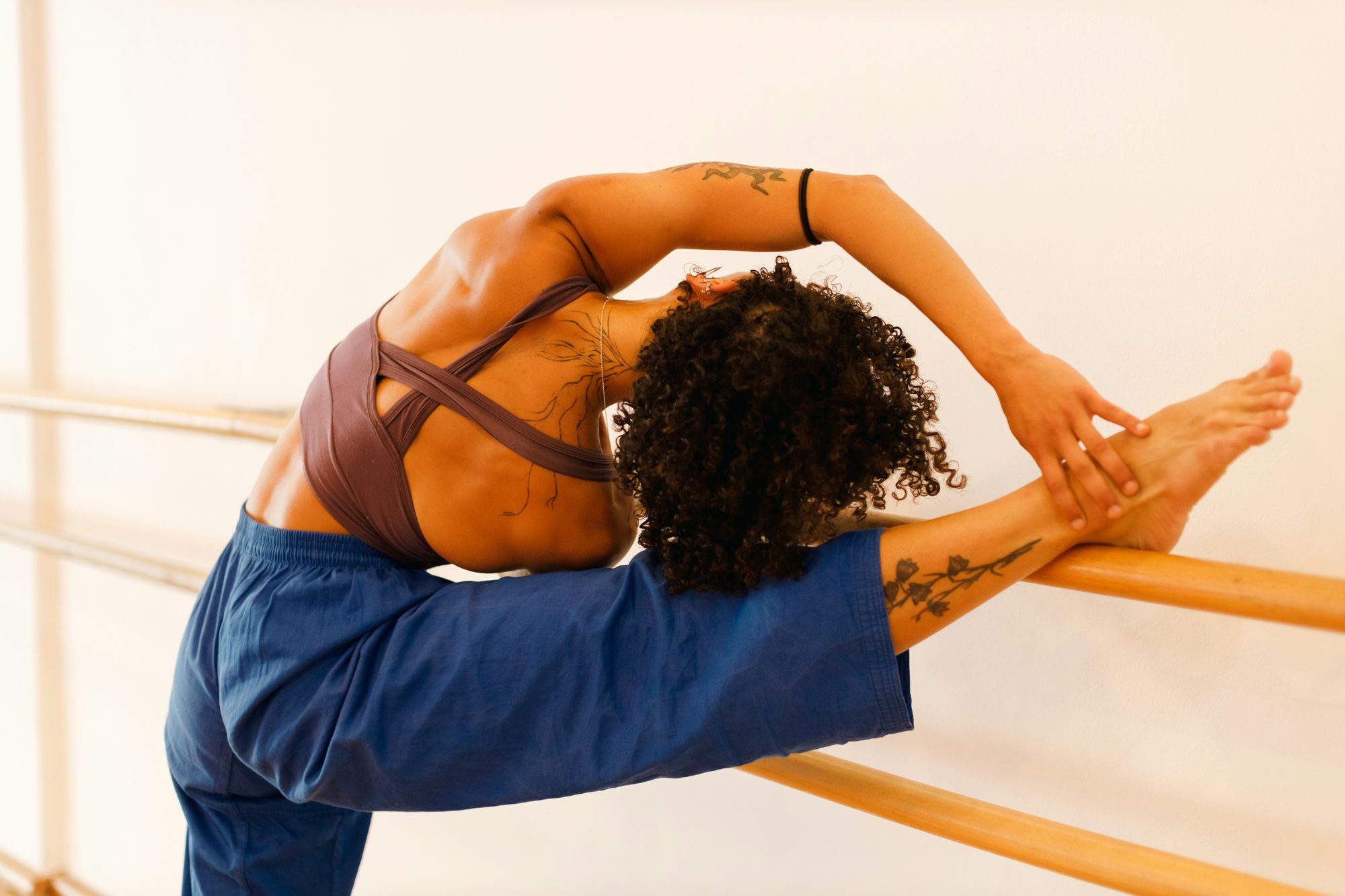 Mujer estirando la pierna sobre la barra de ballet