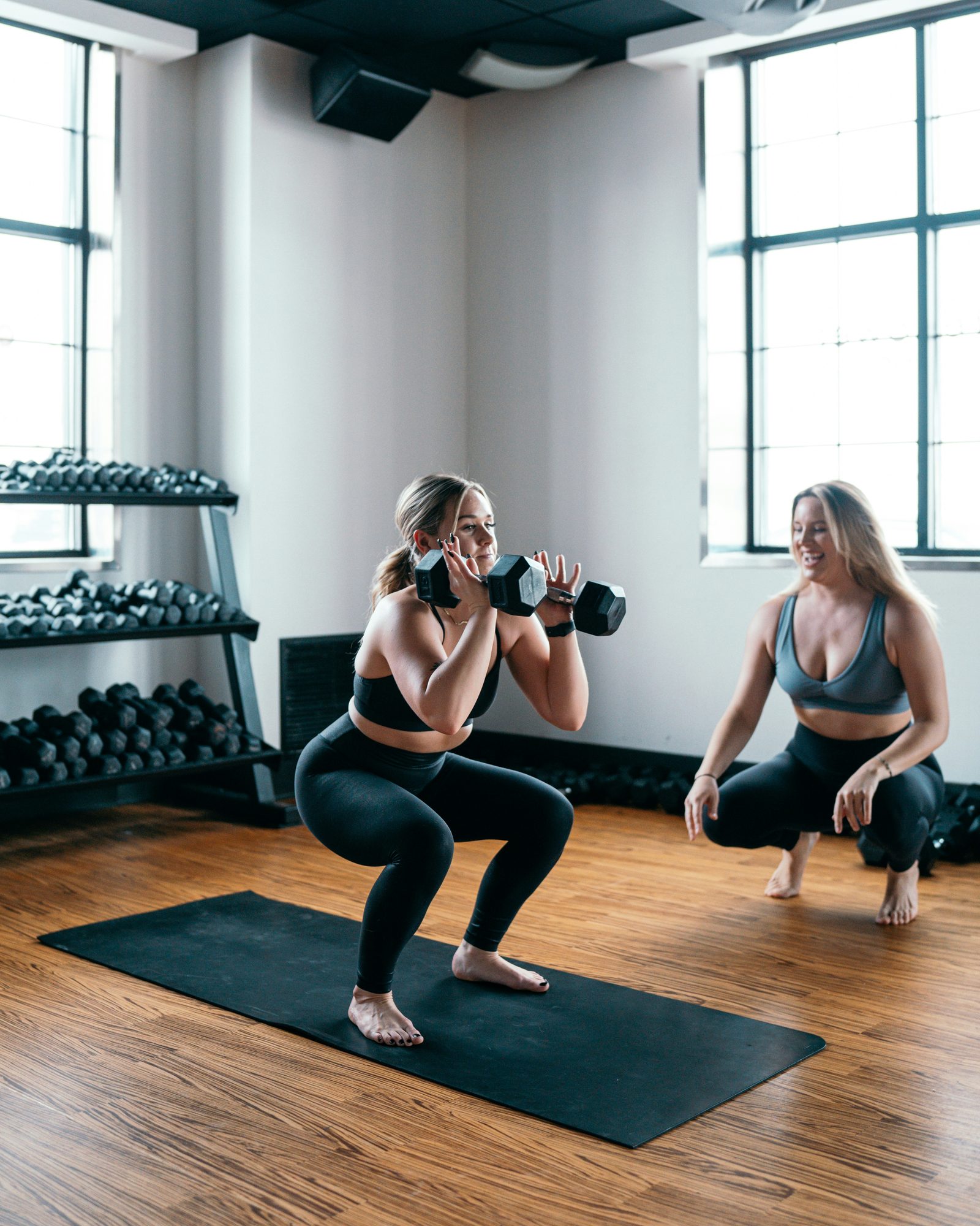 Dos mujeres haciendo sentadillas con mancuernas